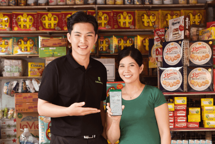 Smiling man and woman in a retail store displaying a smartphone with a mobile app.