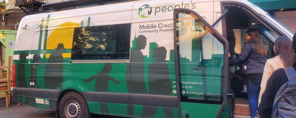 White and green community service van with a mural, open door, and person entering.