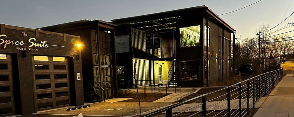 Modern building made of shipping containers for The Spice Suite at dusk with illuminated windows.