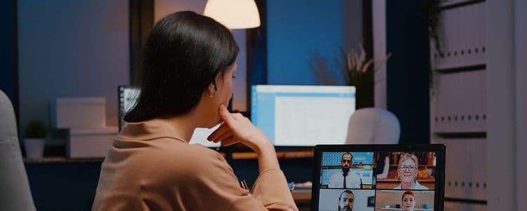 A person seen from behind, participating in a video call on a computer at night.
